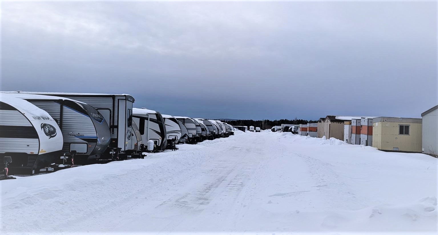 A row of parked recreational vehicles in the snow.